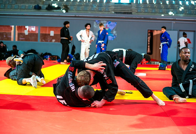 Deux compétiteurs en jiu-jitsu brésilien engagés au sol sur le tapis de compétition