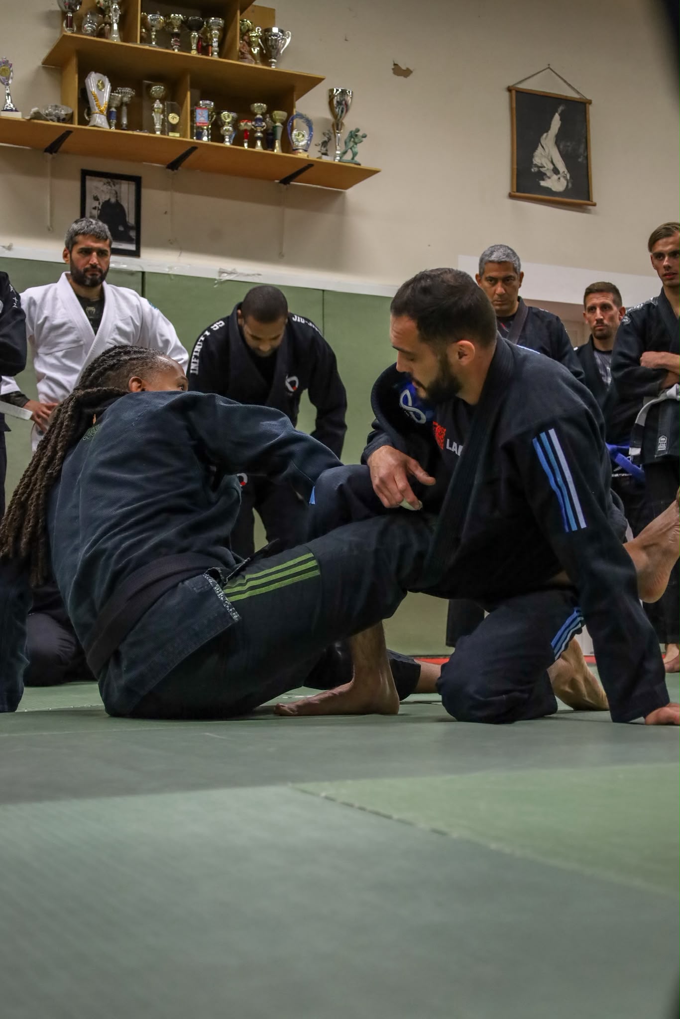 Coach démontrant un travail de garde au sol devant le groupe attentif lors d'un cours de JJB