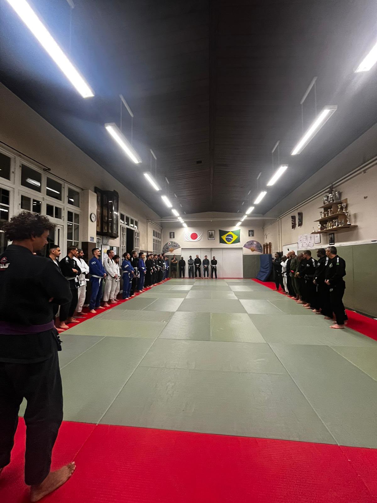 Cours collectif de JJB, pratiquants alignés sous les drapeaux japonais et brésilien au dojo d'Ermont