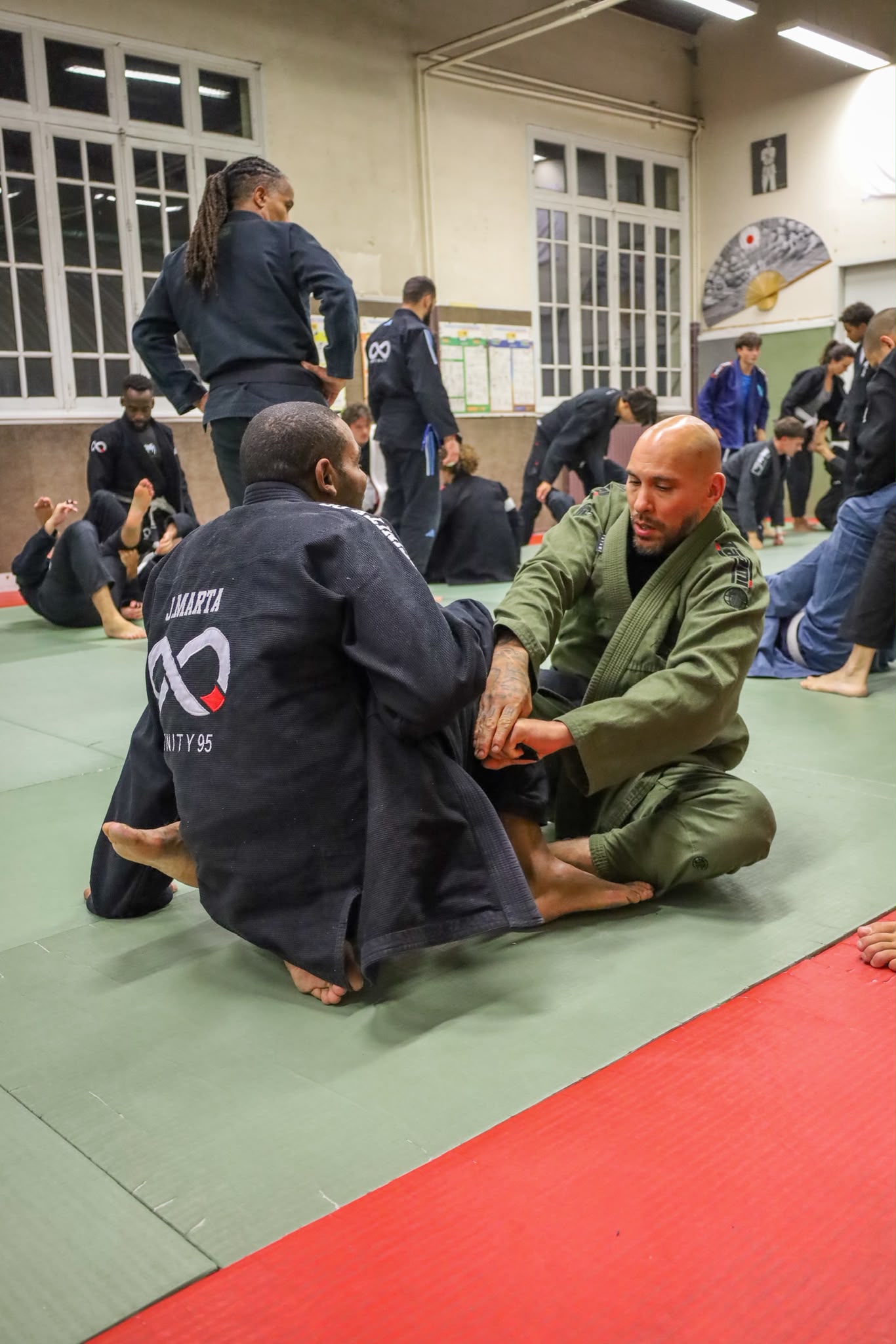 Coach démontrant une technique au sol pendant un cours de JJB